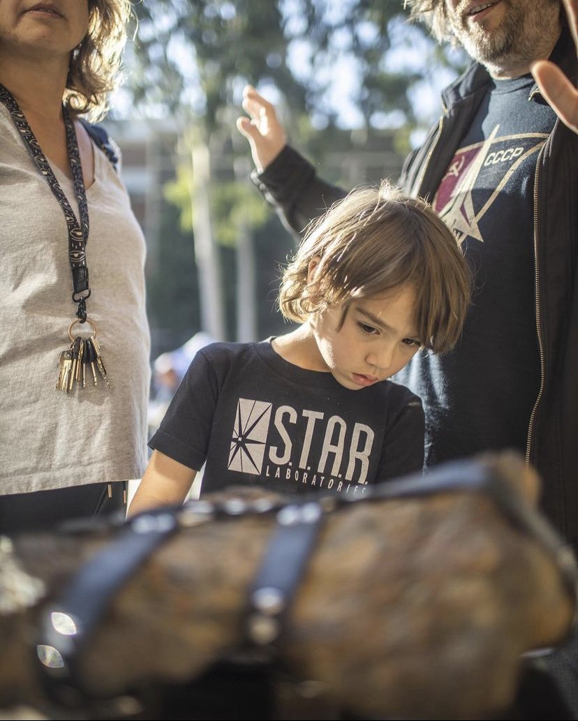 Boy in a S.T.A.R. Labs T-shirt studying the meteorite at UCLA