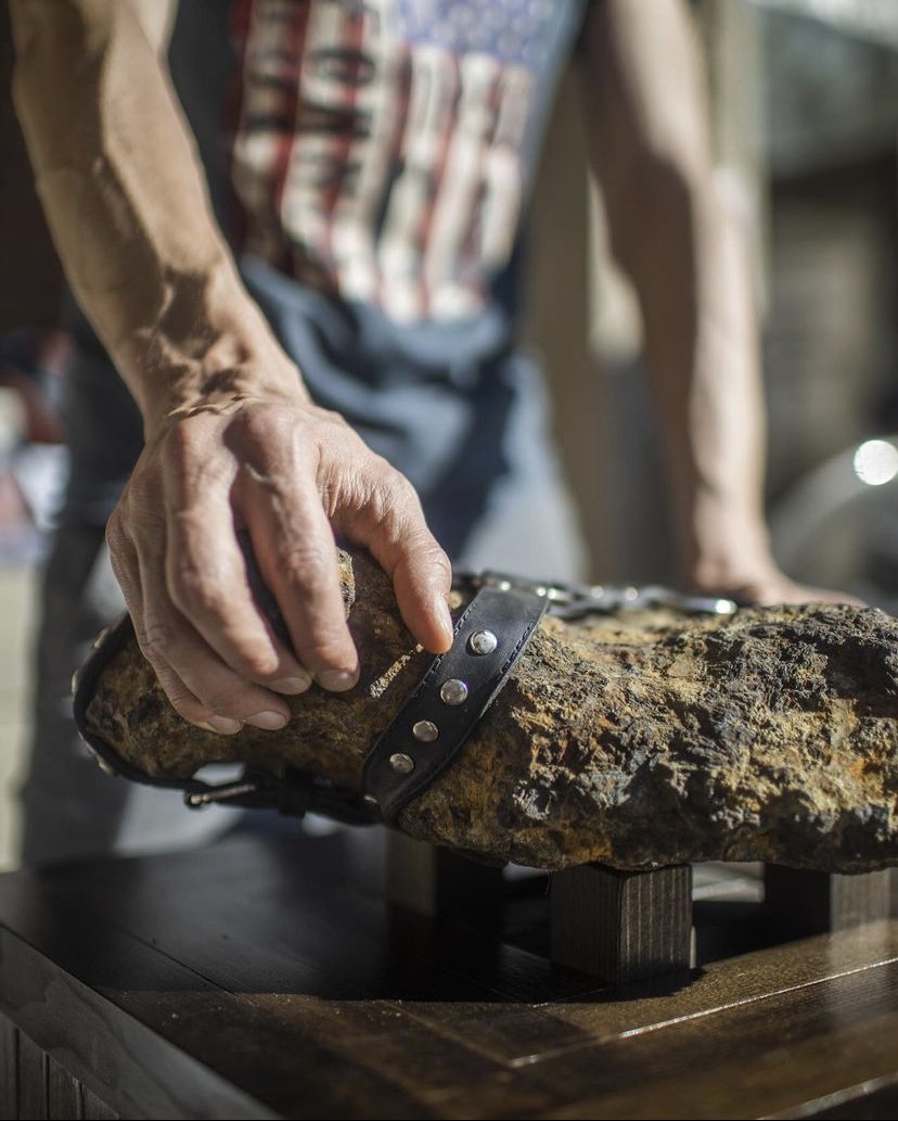Close-up of the Muonionalusta iron meteorite with riveted leather strap on a wooden stand