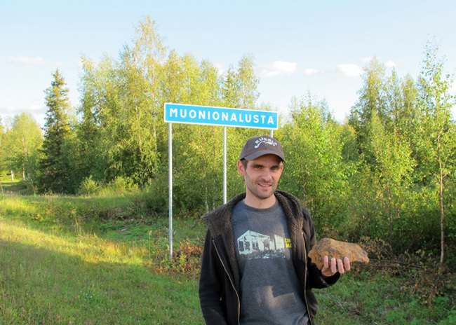Anton Artemev at the Muonionalusta road sign with a meteorite, 2013